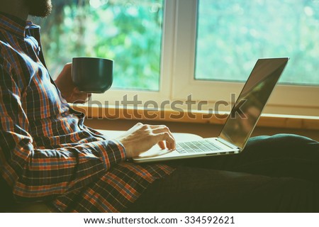 man lying with laptop drinking coffee or tea
