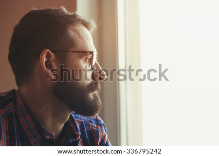 handsome bearded man in checkered shirt and glasses thinking
