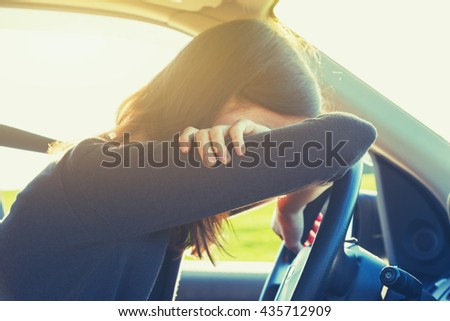 stressed or tired girl in car lying on steering wheel