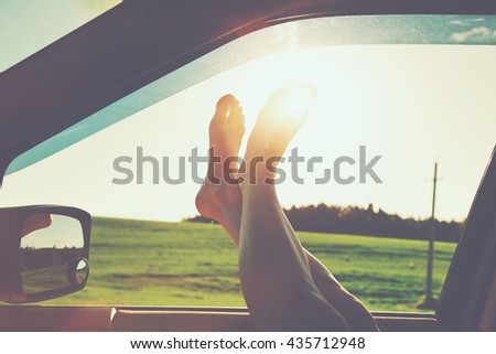 Woman legs out car window. Freedom or traveling concept