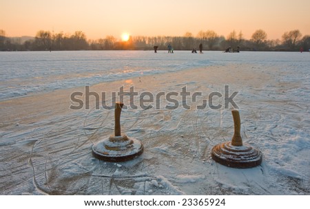 two bavarian curling stones on a frozen lake at sunset