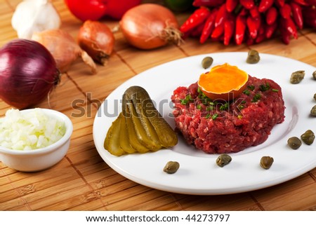 steak tartar with an onion ring and an open egg