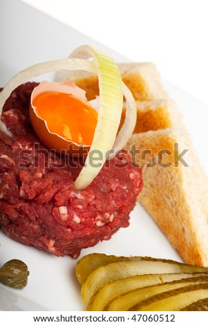 steak tartar with an onion ring and an open egg