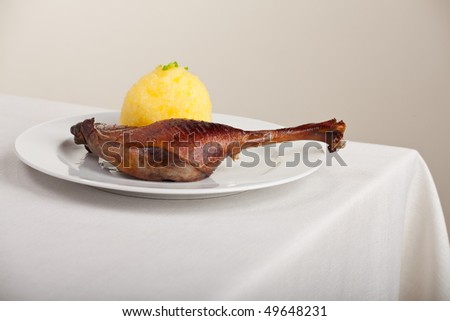 roasted goose leg on linen tablecloth