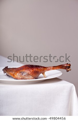roasted goose leg on linen tablecloth