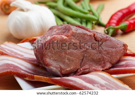 raw meat and bacon stripes on a wooden table