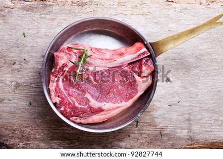 raw t bone steak in a copper pan