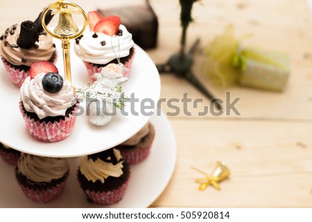 Cupcakes on a cake stand on wood with Christmas tree and gift box on wood on white background. Santa Claus