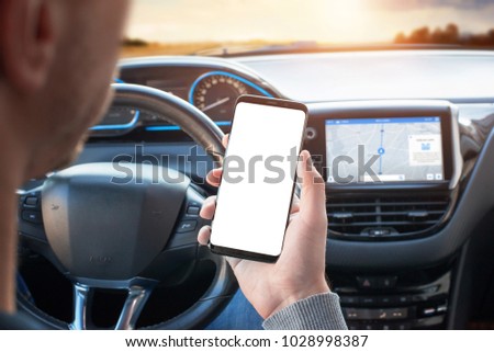 The driver uses the phone while driving. Modern smart phone with round edges. Isolated screen for mockup. Car navigation display in background.