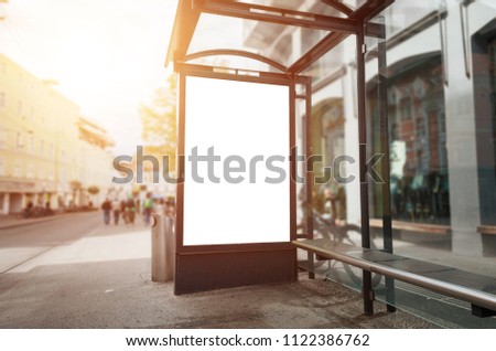 Bus stop billboard mockup. Sun light and street in background.
