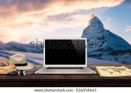 white laptop map hat rope torch on the table with winter mountains in the background mock up presentation