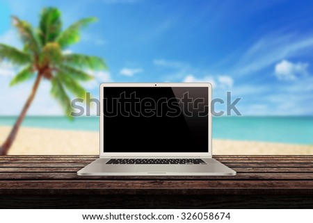 white laptop on the table with a beach palm tree and sea in the background mock up presentation