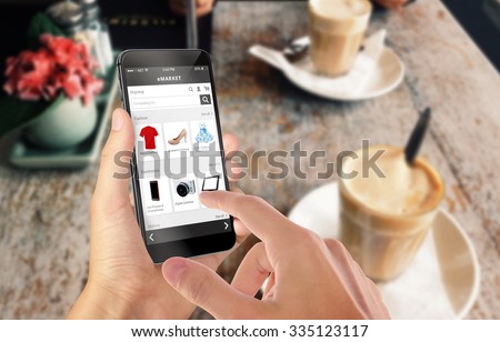 Smart phone online shopping in man hand. Desk with caffe in background. Buy clothes shoes accessories with e commerce web site