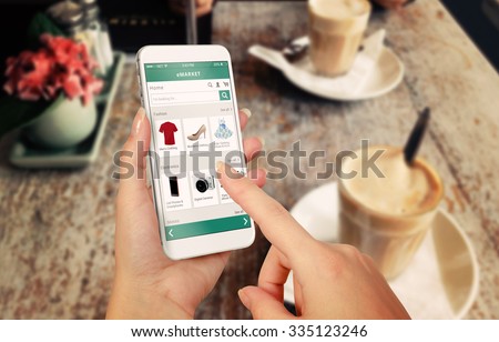 Smart phone online shopping in woman hand. Desk with caffe in background. Buy clothes shoes accessories with e commerce web site