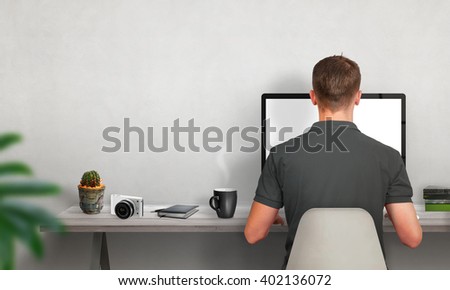 Man work on computer. Coffee, cactus, camera, books on table. Free space on wall for text.