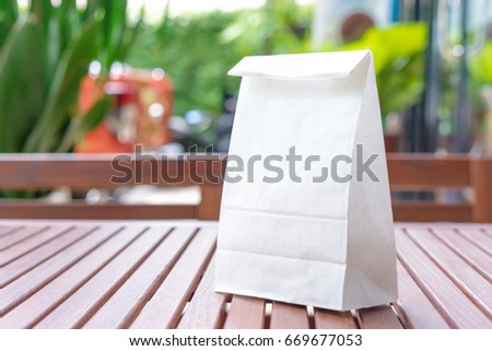 Blank white paper bag for taking away food on a wooden table