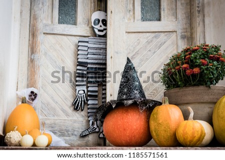 Halloween decorated front door with various size and shape pumpkins and skeletons. Front Porch decorated for the Halloween season.