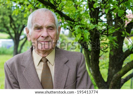 Handsome 80 plus year old senior man posing for a portrait in his garden.