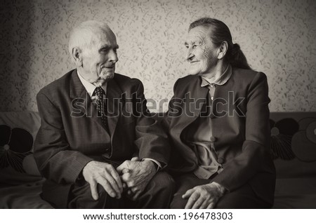 Cute 80 plus year old married couple posing for a portrait in their house. Love forever concept.