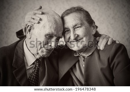 Cute 80 plus year old married couple posing for a portrait in their house. Love forever concept.