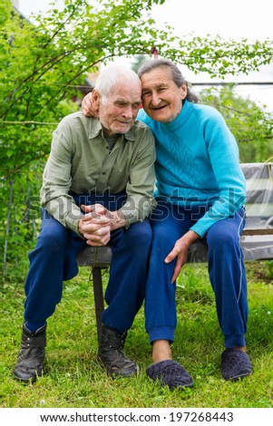 Cute 80 plus year old married couple posing for a portrait in their garden. Love forever concept.