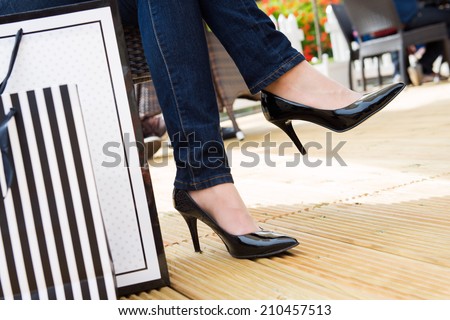 Attractive young female in sexy black high heels enjoying a break after successful shopping, detail shot, with copy space