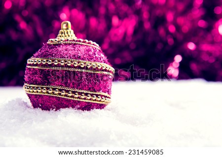 Pink and purple and gold Christmas ball in snow and tinsel, christmas background, christmas banner with copy space