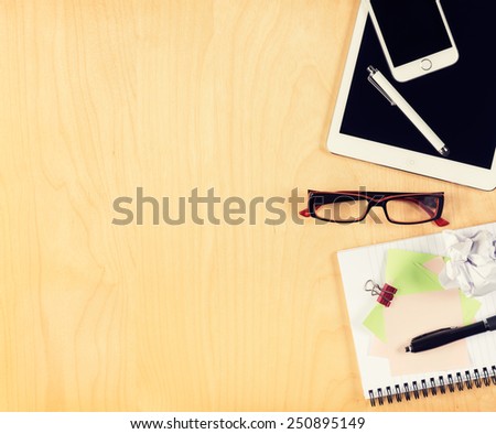 Office table with digital tablet, smartphone, reading glasses and notepad. View from above with copy space