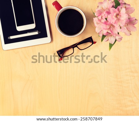 Office table with digital tablet, smartphone, reading glasses and cup of coffee. View from above with copy space