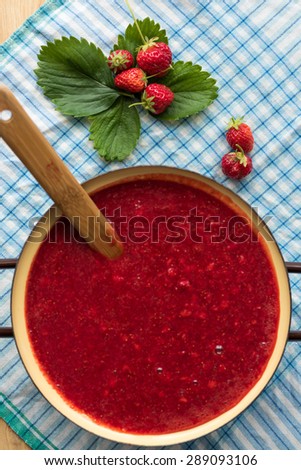 Homemade strawberry jam (marmalade) cooking. Large pot with hot jam and fresh strawberries