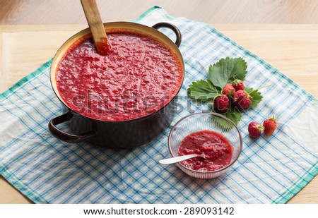 Homemade strawberry jam (marmalade) cooking. Large pot with hot jam and fresh strawberries