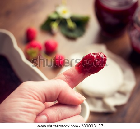 Finger dipped in strawberry jam. Homemade strawberry jam (marmalade) concept.