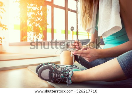 Attractive blond woman with smart phone, resting after gym workout