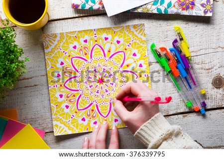 Woman coloring an adult coloring book, new stress relieving trend, mindfulness concept, hand detail