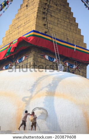 KATHMANDU, NEPAL - MARCH 28, 2014: A man throws orange paint on Boudhanath Stupa as part of the renovation and painting work which will cost four million Nepalese Rupees.