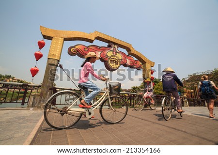 HOI AN, VIETNAM - MAY 12, 2014. Unidentified local woman riding bicycle on the bridge in Hoi An Ancient Town, Quang Nam, Vietnam. Hoi An is recognized as a World Heritage Site by UNESCO.