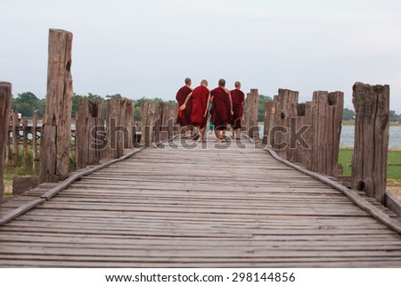 monks from local Buddhist temple in Amarapura crossing U Bein bridge - one of most popular travel destinations in Burma.