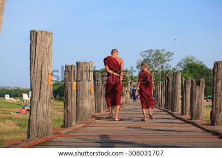 Monks from local Buddhist temple in Amarapura crossing U Bein bridge - one of most popular travel destinations in Burma.