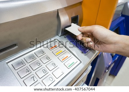 Close up image of a human hand inserting a credit card in the ATM