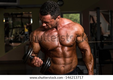 muscular man doing heavy weight exercise for biceps with dumbbell