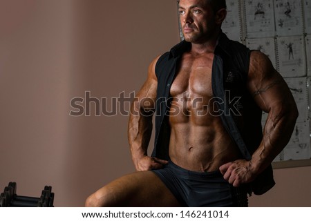 macho bodybuilder posing in black shirt without sleeves
