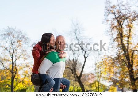 Male Carrying Smiling Female On His Back At Park