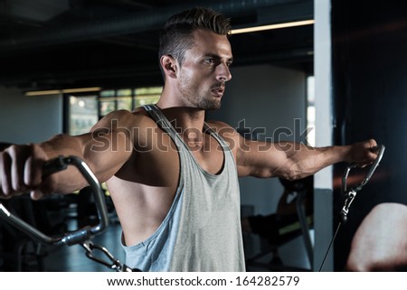Heavy Duty. Body Builder Workout On Cable Machine. Standing Low Pulley Deltoids Raise