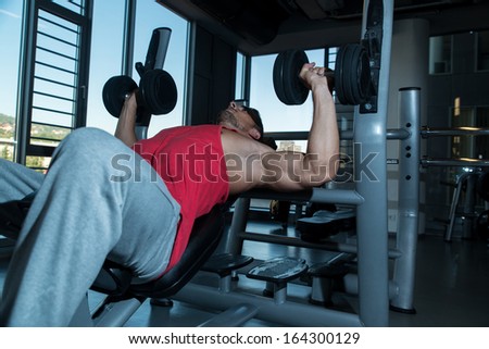 Attractive Fit Men Lying On A Weight Bench Working Out With Dumbbell