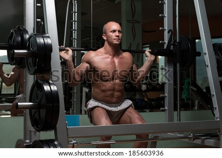 Young Man Performing Barbell Squats - One Of The Best Body Building Exercise For Legs