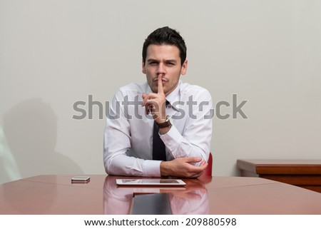 Businessman With Finger On Lips Asking For Silence