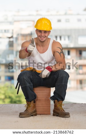 Portrait Of A Construction Worker With Yellow Helmet Making Thumbs Up Sign