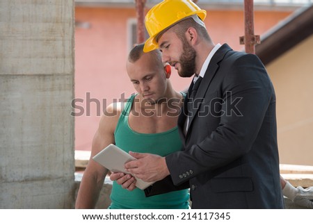 Businessman And Industrial Worker Looking At Tablet PC - Group Of Male Architect And Construction Worker On Construction Site
