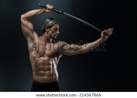 Muscled Male Model In Studio With A Sword - Portrait Of A Handsome Muscular Ancient Warrior With A Sword