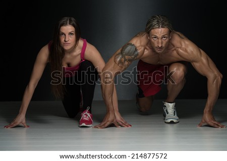 Strong Muscular Couple Kneeling On The Floor - Almost Like Sprinter Starting Position